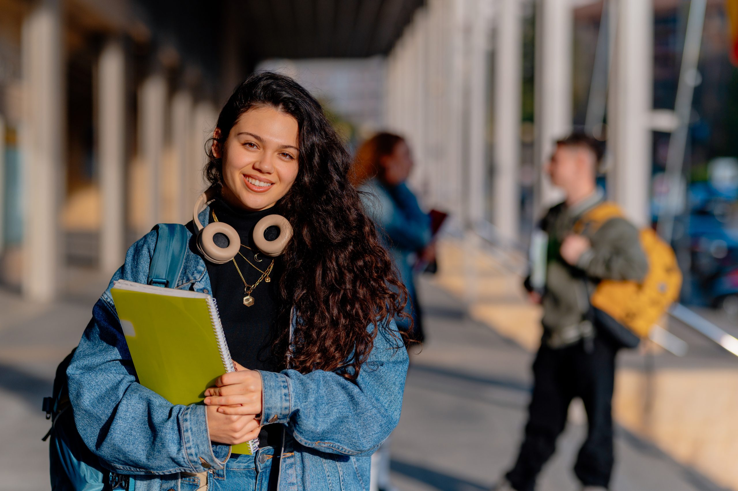 estudiante viendo a la camara mientras carga sus libros